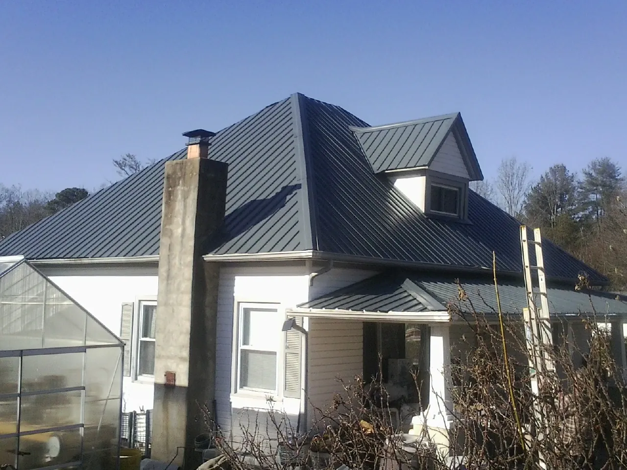 Dark blue standing seam metal roof on a white farmhouse with dormer — Slate & Tile Roof Repair by Roofing Brothers in Morgan Hill