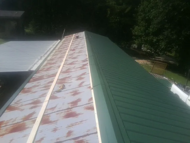 Old rusted panels beside newly installed green metal roofing — Wind Damage Roof Repair by Roofing Brothers in Morgan Hill