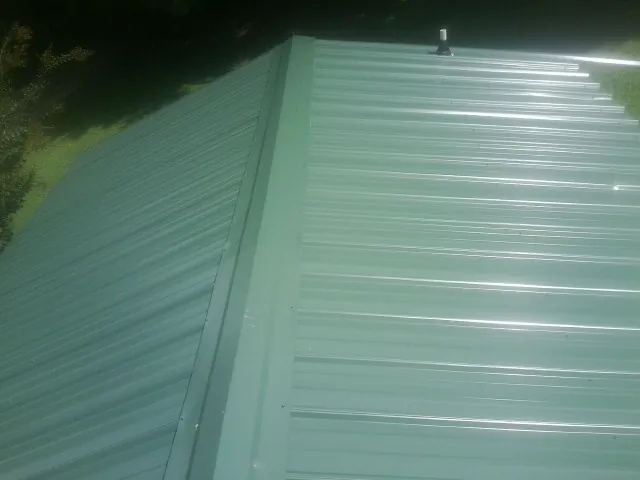 New green metal panels meeting at the ridge of a roof — Flat Roof Repair work by our crew in Morgan Hill
