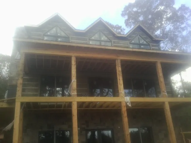 Dormers and porch framing on a large log home under construction — Roof Coating work by our crew in Morgan Hill