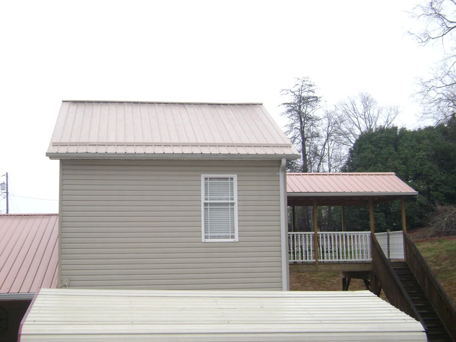 Tan metal roofs on a two story addition and attached porch, from a Roof Replacement job in Morgan Hill