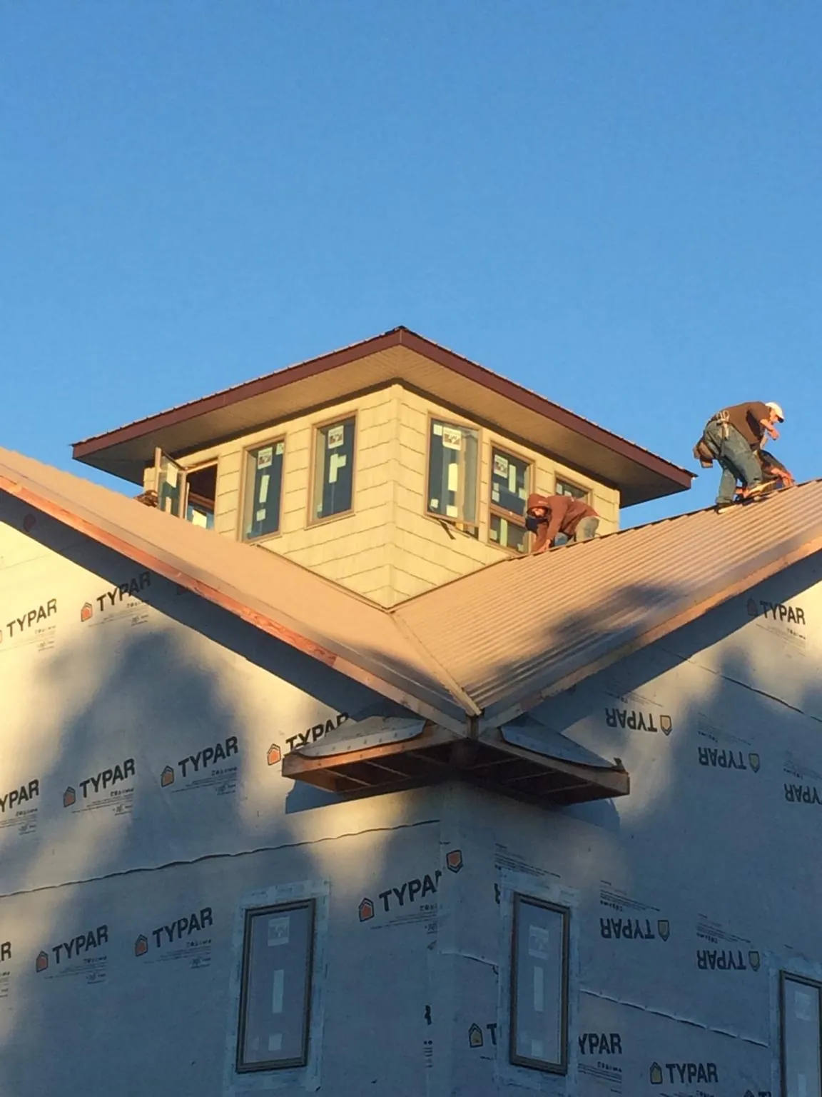 Roofers working around a rooftop cupola on a new metal roof at sunset — Roof Waterproofing in Morgan Hill by Roofing Brothers